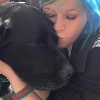woman kissing her black dog on the head