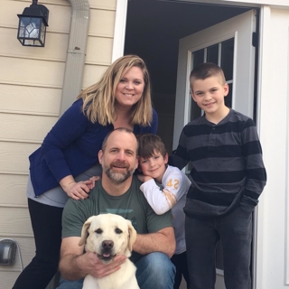 family of four posing with their white lab dog