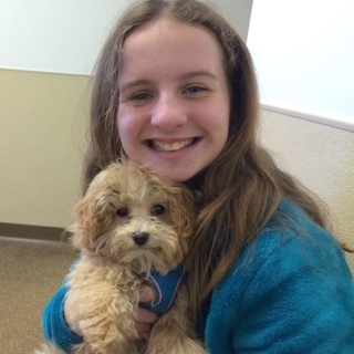 young girl holding a small tan puppy