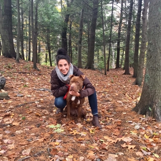 dog with smiling woman in woods