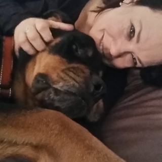 woman cuddling with her black and tan dog